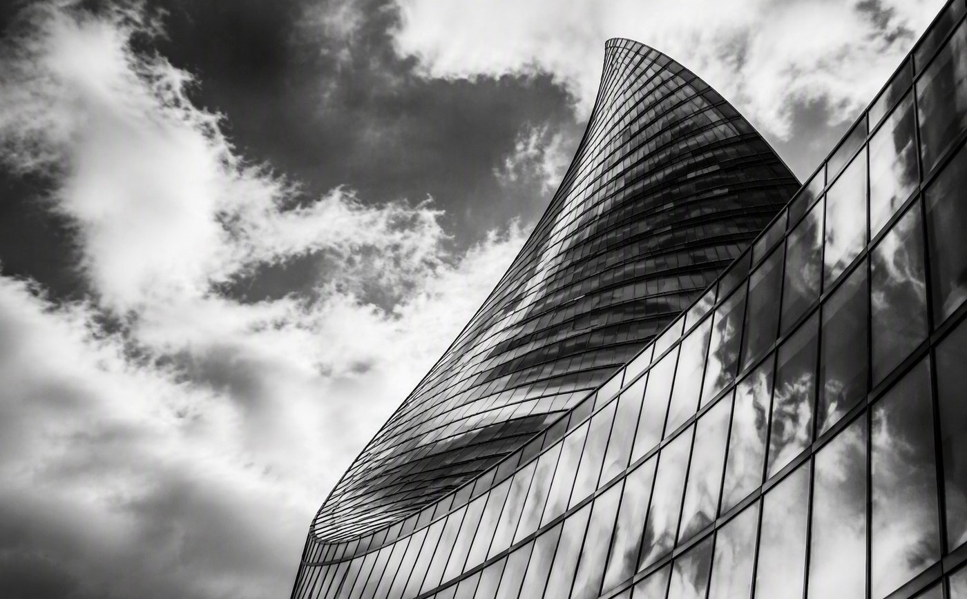Fine-art monochrome study of a glass tower against moving clouds